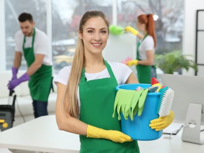 Young female worker holding cleaning supplies at office